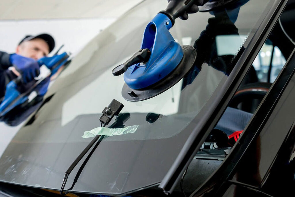 Auto glass technician replacing a cracked windshield on a vehicle